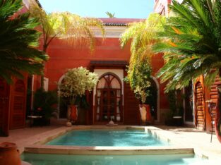 Binnenplaats met zwembad en palmen in een traditionele riad in Marrakech