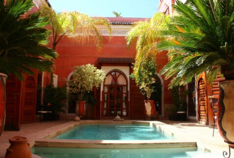 Binnenplaats met zwembad en palmen in een traditionele riad in Marrakech