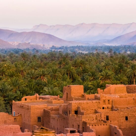 Lemen kasbah tussen de palmentuinen bij zonsondergang in Zuid-Marokko