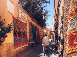 Fietser in een smal steegje vol kleurrijke Berbertapijten bij Dar Si Said in de medina van Marrakech