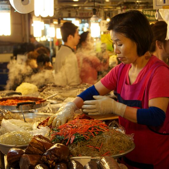 Verkoopster bereidt japchae op de Gwangjang-markt in Seoul